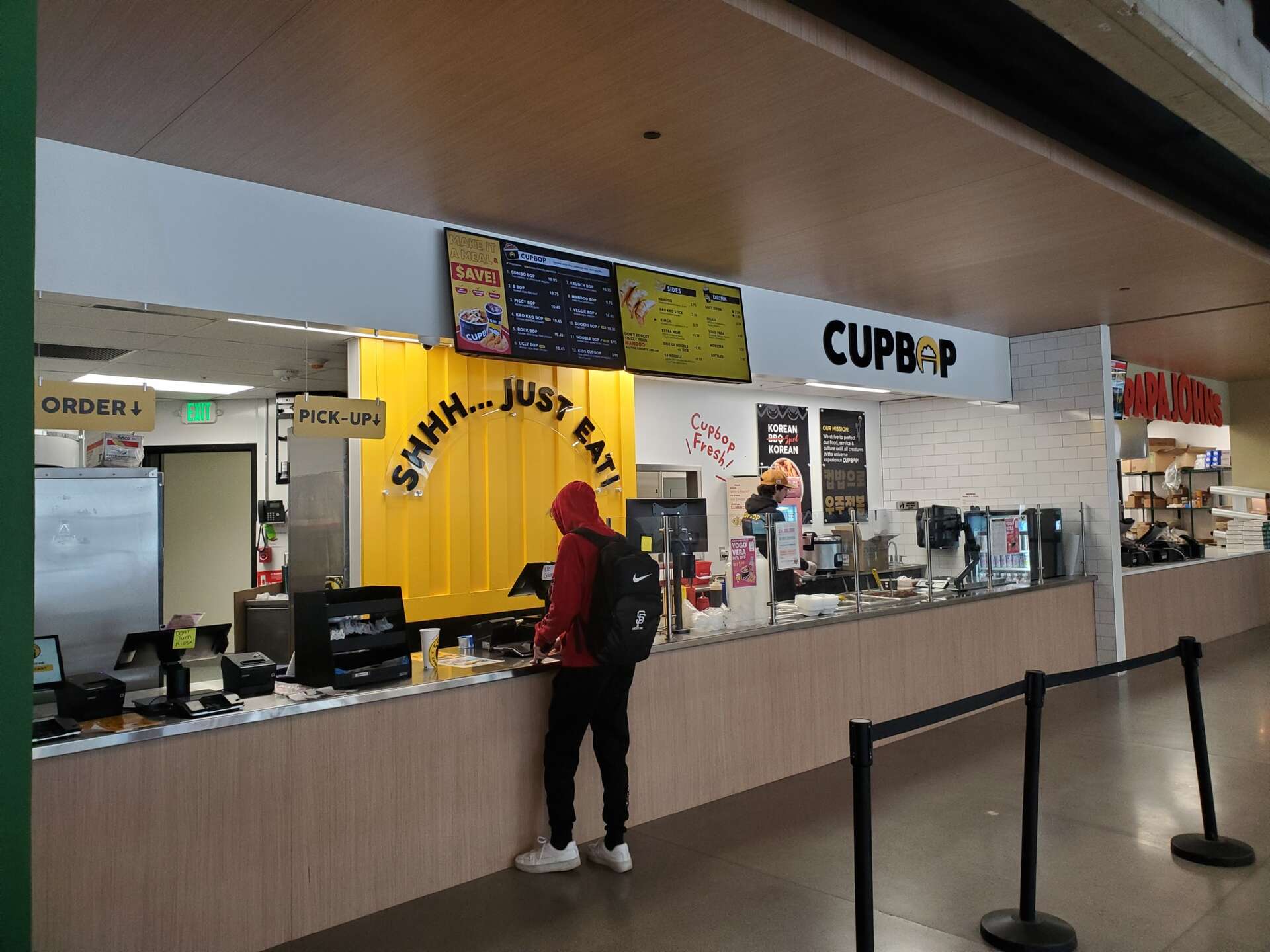 A man waits by the Cupbop order-counter for his food.