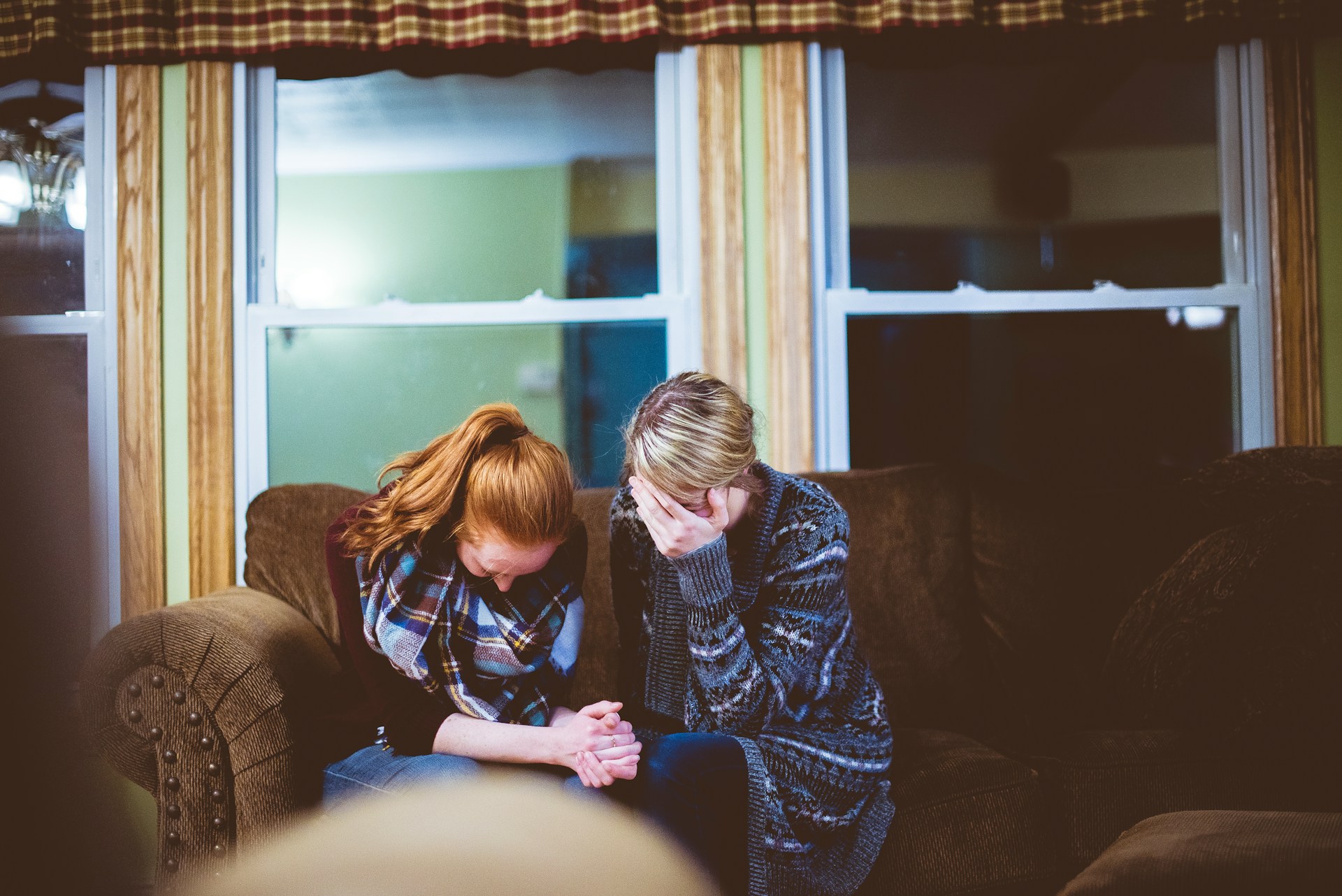 Two women sitting with their heads down in distress.