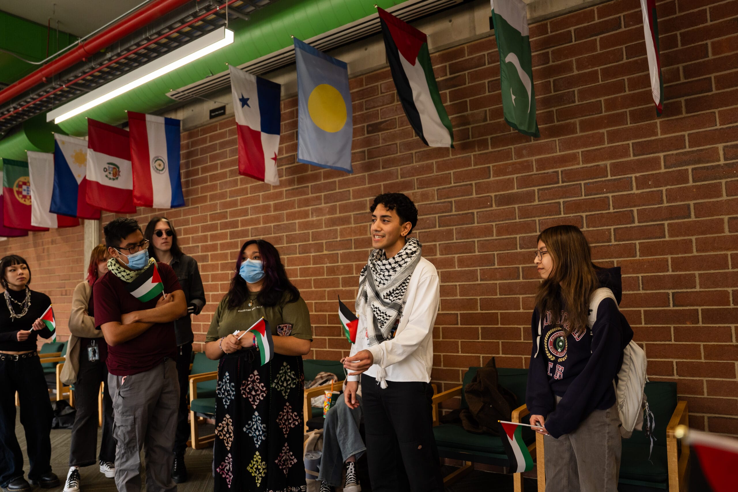 Members of the UVU Keffiyeh club demonstrate in front of the Palestine Flag in the Hall of Flags